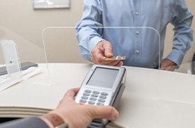 Man using card to pay for treatment at dental office front desk