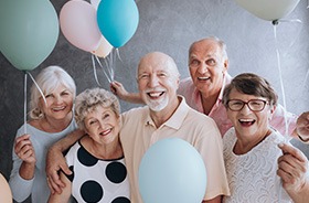 Group of senior friends holding balloons at party