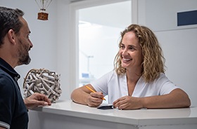 Friendly dental receptionist helping patient with paperwork