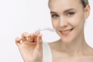 Smiling woman holding an Invisalign aligner